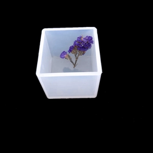 Macro view of a square silicone resin mold with a purple dried flower inside for DIY crafts