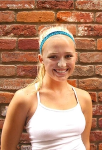 Close-up of a blue sequin elastic headband worn by a girl against a brick wall background