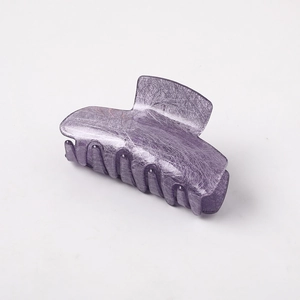 Macro shot of purple hair claw clip with unique brushed texture on a white background