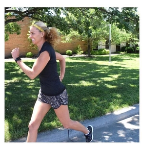 Dynamic view of a woman running outdoors wearing a yellow sequin elastic headband