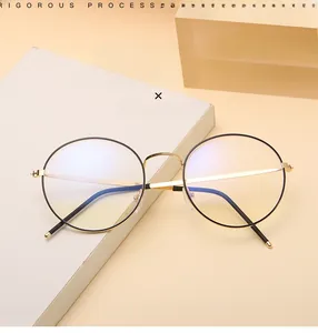 Detail of round metal glasses frame in black and gold finish on a minimal background