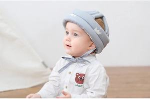 Adorable infant in a grey crown pattern safety helmet for walking and head protection