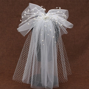 Detail of bridal hair bow with white pearls and soft tulle ribbon for weddings