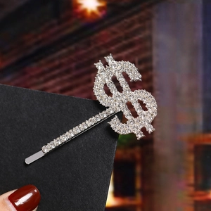 Detail of silver dollar sign hair clip with sparkling rhinestones on black card