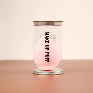 Pink teardrop beauty sponge blender in a clear cylindrical container with silver lid