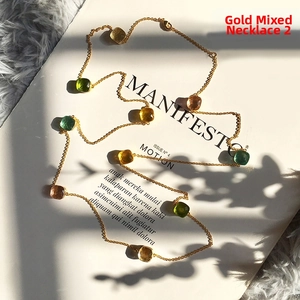 Detail of gold chain necklace with multi-color sugar-loaf cut gemstones in bezel setting