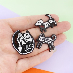 Detailed view of skeleton enamel animal pins held in hand featuring cat and dog motifs