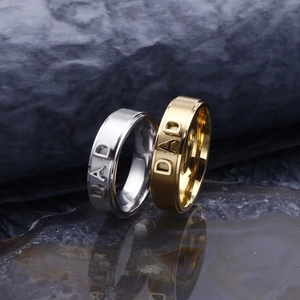 Gold and silver stainless steel DAD rings with a brushed finish on a dark stone base