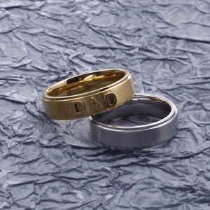 Gold and silver stainless steel men's rings with DAD engraving on a textured surface