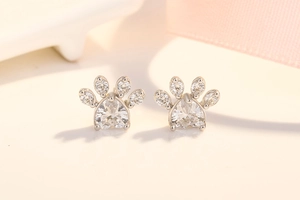 Macro shot of silver paw stud earrings with heart-shaped white zircon and crystals