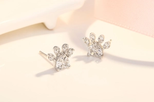 Macro view of heart-shaped white zircon paw print stud earrings with rose gold plating