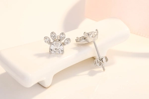 Detail of silver cat paw earrings with heart-shaped cubic zirconia and rose gold plating
