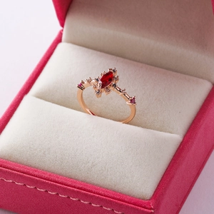 Detail of a vintage rose gold ring with a red marquise cut stone and zircon accents