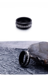 Macro view of two-tone black and silver stainless steel ring with industrial gear texture