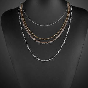 Layered 18k gold and silver stainless steel cable chains on a black bust display