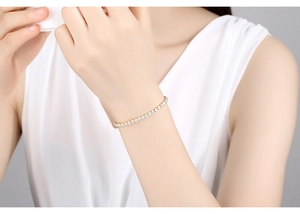 Close-up of a classic gold-plated tennis bracelet with white cubic zirconia on a wrist