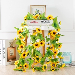 Close-up of artificial sunflower vine with green leaves on a white table for home decor