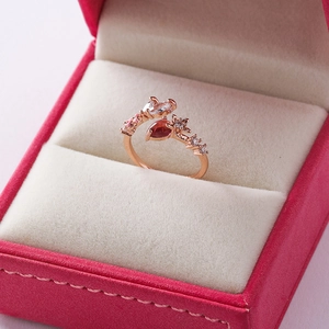 Detail of rose gold flower ring with pear-cut brown gemstone in pink velvet box