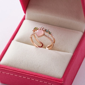 Macro detail of rose gold double-layer open ring with pink heart stone and floral accents