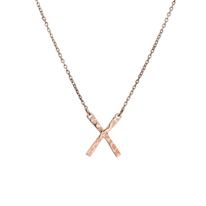 Détail du pendentif X en or rose avec texture martelée sur un collier en acier inoxydable