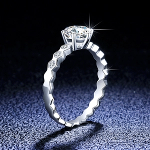 Macro detail of six-prong moissanite ring with wavy band and honeycomb side stones