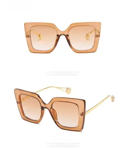 Detail of square oversized sunglasses with gradient tea lenses and pearl-tipped gold temples