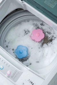 Macro view of flower-shaped laundry lint catcher floating in a washing machine drum