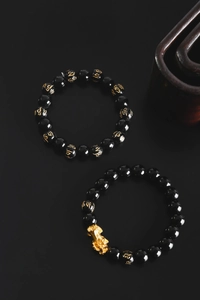 Detailed close-up of obsidian prayer beads with gold PiXiu charm and engraved mantras