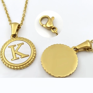 Detail of 18K gold coin pendant with white shell inlay, letter K, and polished back view