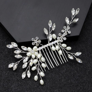 Macro detail of silver bridal hair comb with pearls and rhinestones on black base