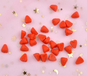 Close-up of DIY resin strawberry charm accessories on pink starry background