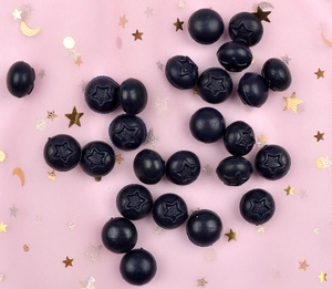 Close-up of blue star-patterned resin beads for DIY jewelry on pink sequin fabric