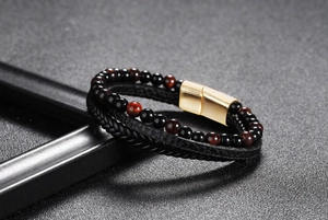Detail of double-layer men's bracelet with black leather cord, beads, and gold magnetic clasp