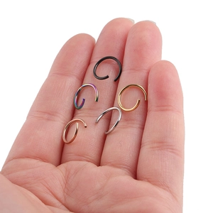 Detailed view of five colorful stainless steel open rings held in a palm for size scale