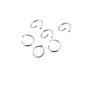 Detailed view of silver stainless steel jump rings and piercing hoops on white background