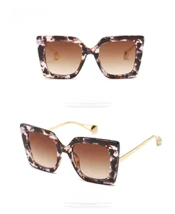 Close-up of oversized square sunglasses with ink-patterned frame and pearl temple tips