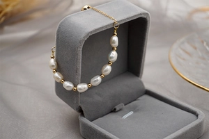 Macro shot of freshwater pearls and gold beads on a titanium chain in a jewelry box
