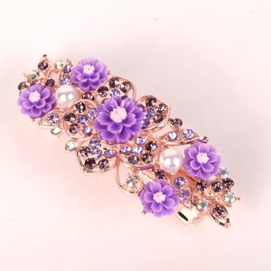 Dettaglio di pettine per capelli in oro rosa con fiori viola e perle bianche eleganti