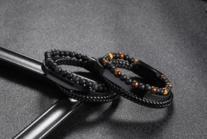 Detail of woven leather bracelets with tiger eye stones and matte beads on black background