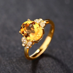 Detail of 18k gold ring with large oval yellow gemstone and diamond butterfly accents