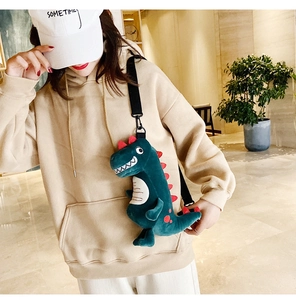 Détail du sac à bandoulière dinosaure en peluche verte avec une sangle noire réglable