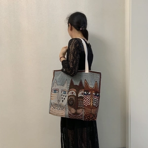 Artistic cat pattern tote bag shown on model's shoulder with cream fabric strap