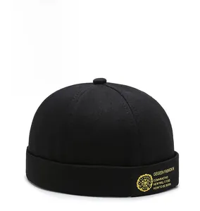 Detail of black brimless docker cap featuring gold GEGEEN FASHION embroidered patch
