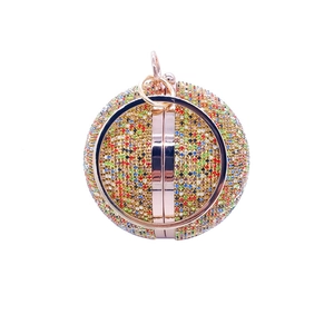 Close-up of a spherical evening bag with colorful rhinestones and rose gold handle