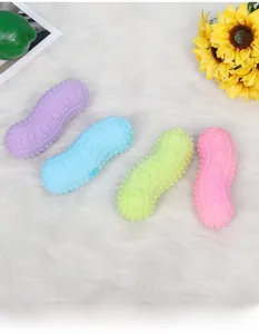 Peanut-shaped rubber dog chew toys with textured surface on a white plush background