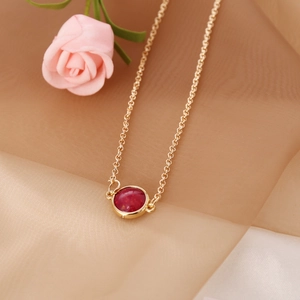 Elegant gold chain necklace with a vintage round red gemstone pendant on white fabric