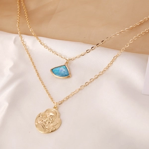Detail of gold layered necklace with blue fan pendant and coin portrait on silk