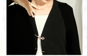 Close-up of gold safety pin brooch with white pearls and crystals on black cardigan