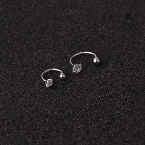 Silver horseshoe barbell earrings with clear cubic zirconia stone on textured background
