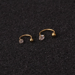 Golden C-shaped cartilage studs with 4-claw zircon in two sizes on a textured background